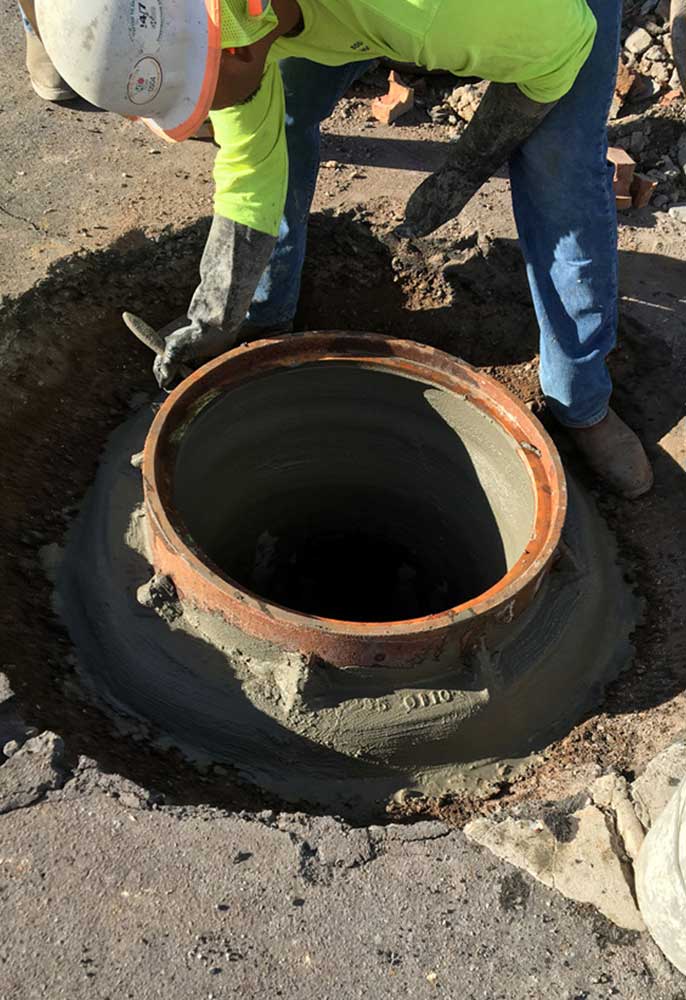 Worker sealing manhole frame and collar.